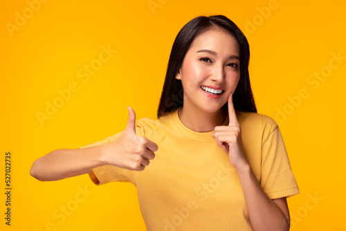 Happy woman take care tooth Give thumb up Young lady has nice smile fresh breath Beautiful asian girl has beautiful tooth, white teeth nice tooth alignment Pretty female show tooth Yellow background