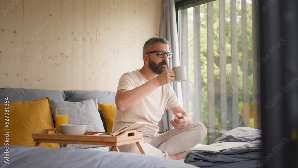 Mature man having breakfast and working in tiny house, in front of nature. Freelancer office concept Mature man having breakfast and working in tiny house, in front of nature. Freelancer office concept