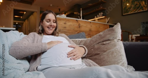 Heavily pregnant woman gently rubbing her tummy and talking to the unborn baby