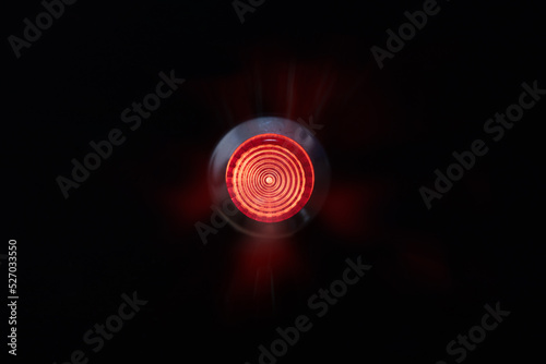 Red alert lamp or warning indicator on black panel glowing. Red alert lamp, status indicator, warning lamp or button.