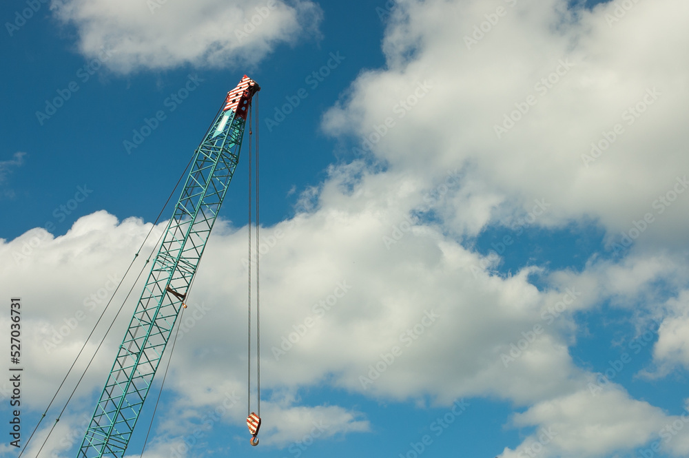 boom tower crane, pictured construction crane on the background of blue sky and clouds