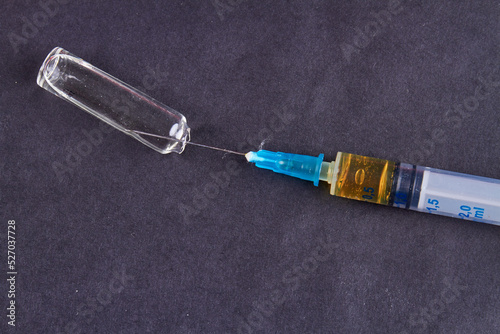 Close-up syringe with glass ampulla on black background. Drug use or vaccination concept.
