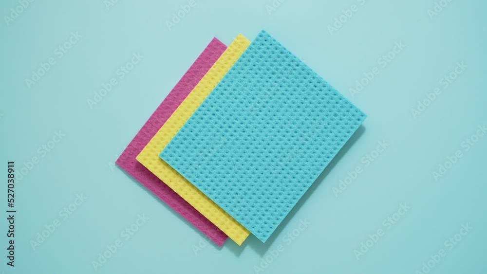 Colorful kitchen sponge cloths. Cleaning essential concept. Isolated on blue background Colorful kitchen sponge cloths. Cleaning essential concept. Isolated on blue background