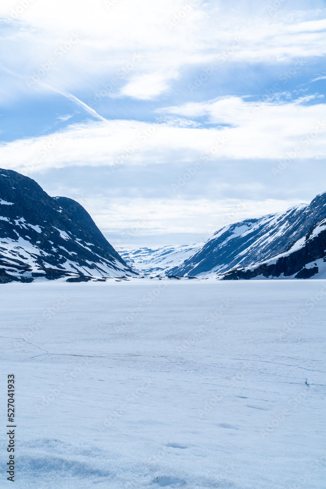 Landscape of a frozen lake with mountains in the background and lots of snow in Norway.