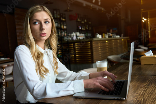 Beautiful women with blonde hair using laptop at cafe for business purpose. Freelancer manager concept.