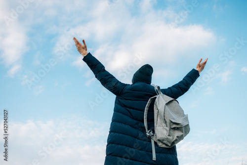 Back view of young woman traveler in dark blue down jacket