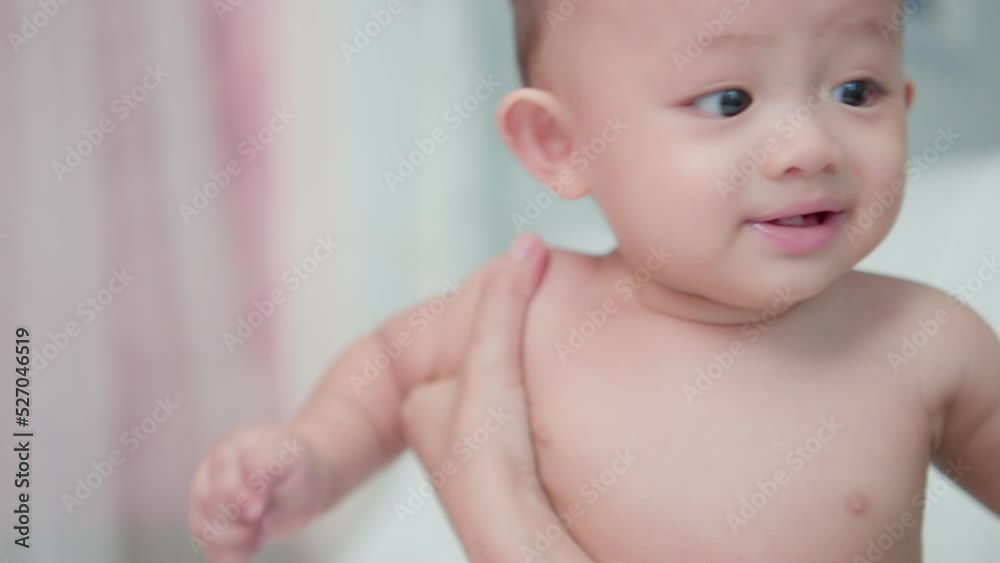 Authentic shot of portrait face cute asian newborn baby in bedroom. While mother takes care nearby, Happy family time. Innocent little new infant adorable. Parenthood and Mother Day concept.