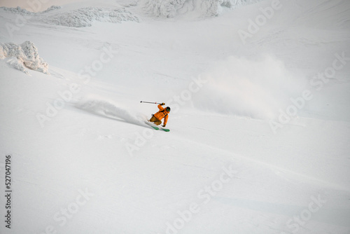 extreme freerider skier quickly riding down on snow-covered mountain slope