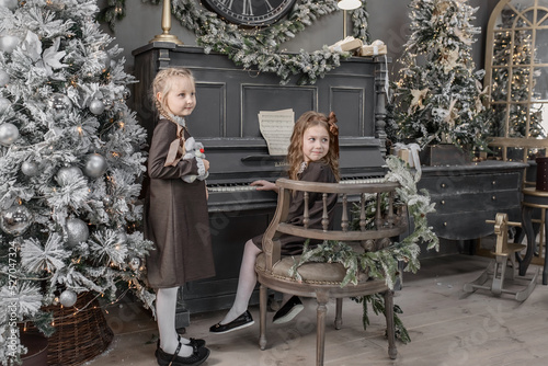 Two cute 5-6-year-old girls on a piano background in Christmas and New Year decorations. Retro style
