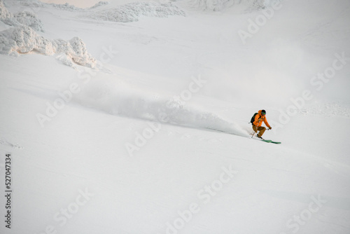 freerider skier quickly riding down on snow-covered mountain slope