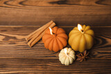 Autumn composition.Pumpkin candles,spicy star anise spices and cinnamon on a brown wooden background.Cozy home decor.Halloween concept.Happy Thanksgiving.Flat lay.Copy space.