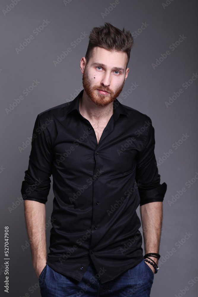 Handsome young man in casual clothing posing on grey background