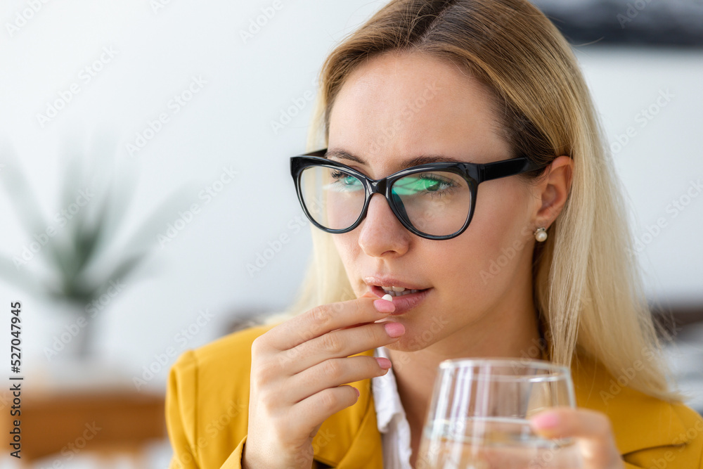 Portrait of young business woman feeling unwell, drinking painkiller, headache pill or antidepressants. Effects of big stress Portrait of young business woman feeling unwell, drinking painkiller, headache pill or antidepressants. Effects of big stress