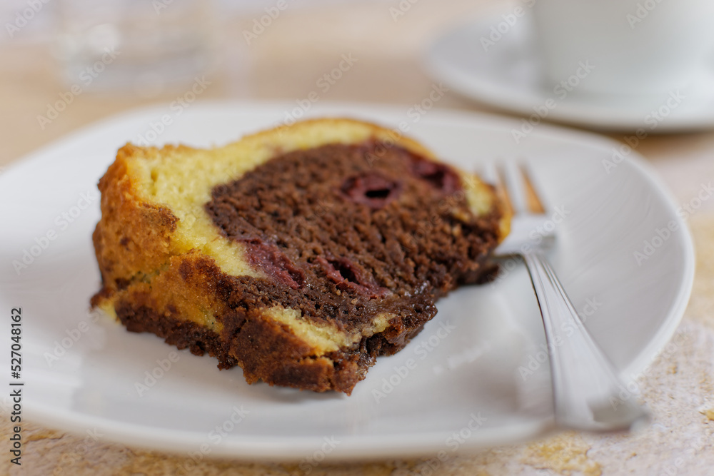 A piece of marble cake with cherries served on a plate. Close-up with selective focus.