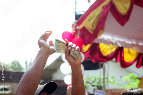 A person's hand holding banknotes or Indonesian state money