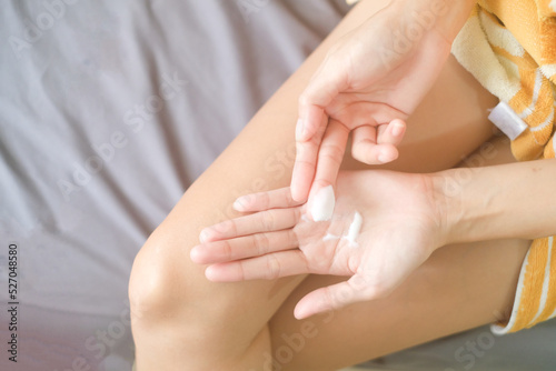 Asia woman applying moisturizing cream/lotion on hands, beauty concept. © BoszyArtis