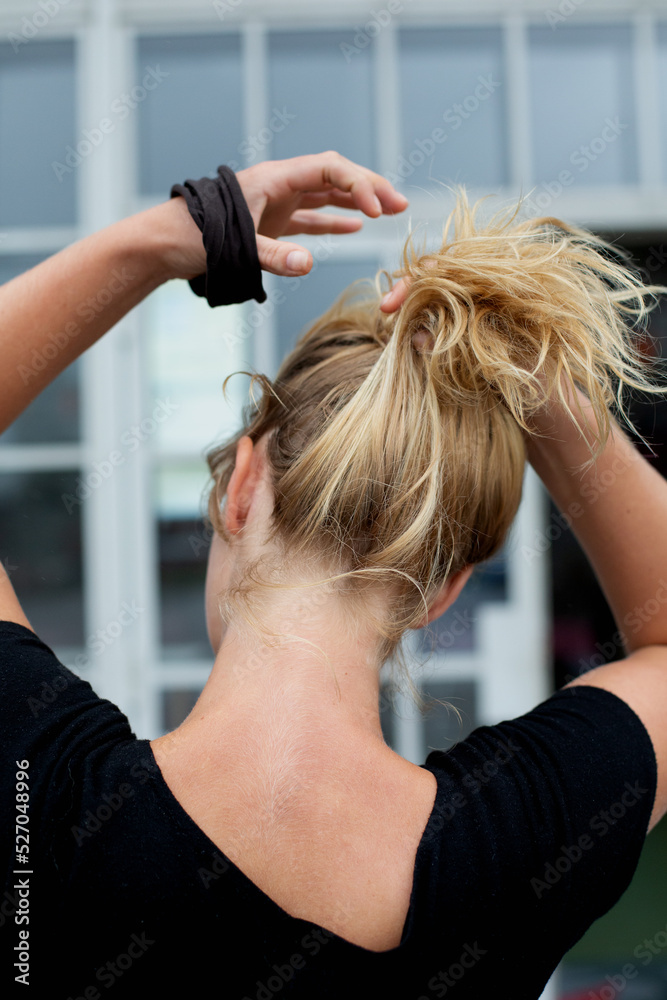 Fototapeta premium Blond-haired girl making a knot with her hair