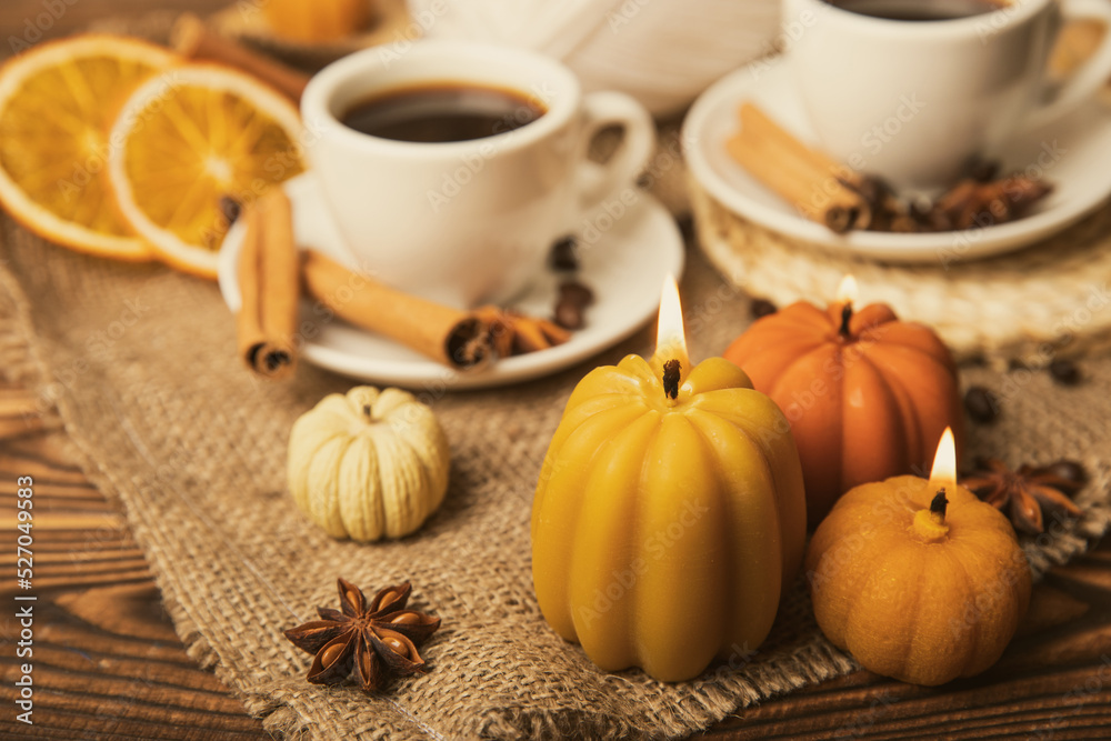 Candles in the form of pumpkins with fragrant coffee on a background of spicy spices of star anise and cinnamon on a brown wooden background.Cozy home decor.Halloween concept.Happy Thanksgiving. Candles in the form of pumpkins with fragrant coffee on a background of spicy spices of star anise and cinnamon on a brown wooden background.Cozy home decor.Halloween concept.Happy Thanksgiving.