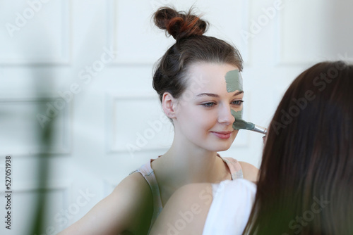 Two friends bonding over a relaxing facial treatment on the sofa, captured in a fun and trendy lifestyle stock photo.