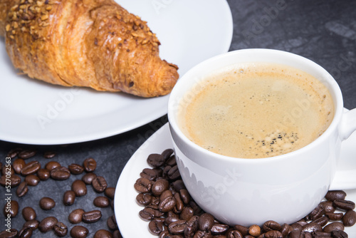 White cup of coffee and fresh croissant with chocolate for breakfast