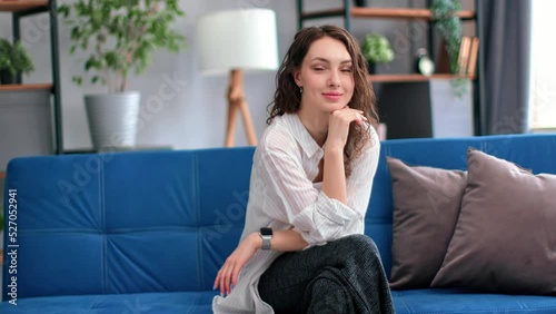 Wallpaper Mural Cute young brunette curly female smiling with positive emotion relaxing sitting on blue couch Torontodigital.ca