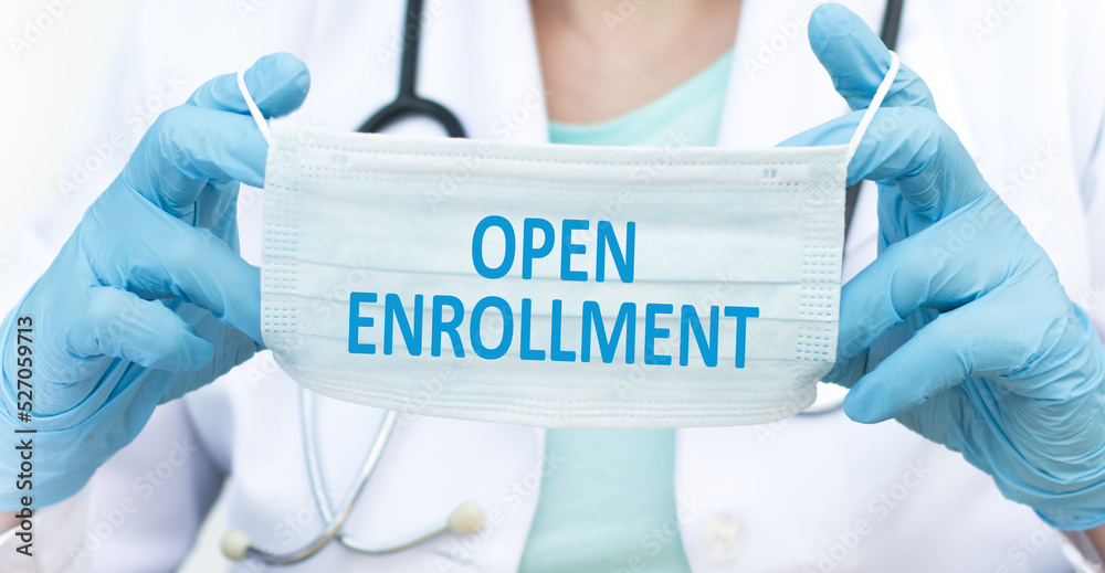Open enrollment text on a protective blue mask in the hands of a doctor, medical concept Open enrollment text on a protective blue mask in the hands of a doctor, medical concept