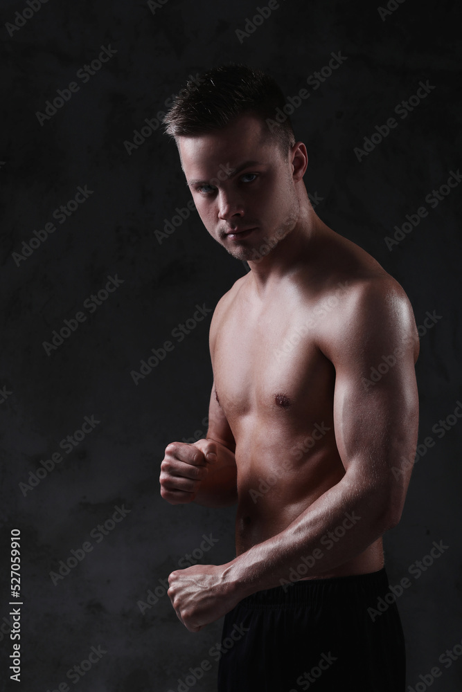 Fototapeta premium Sculpted to Perfection: Male Model Showcases His Fit Physique in a Studio Photoshoot