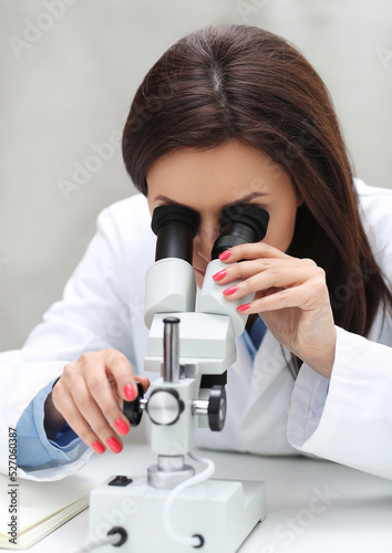 a woman in a lab coat looking through a microscope, portrait of a female pathologist, microscopy, under a microscope, in laboratory, sitting on a lab table, in a laboratory