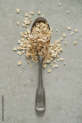 Healthy dry oatmeal in metallic spoon on the table