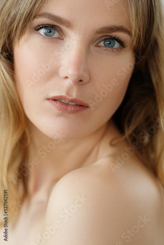 Close view of young blond woman looks at camera and pose at home