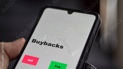 An investor's analyzing the buybacks etf fund on screen. A phone shows the ETF's prices stocks to invest