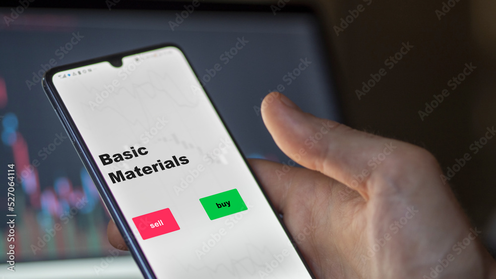 An investor's analyzing the basic Materials etf fund on screen. A phone shows the ETF's prices basic materials to invest An investor's analyzing the basic Materials etf fund on screen. A phone shows the ETF's prices basic materials to invest