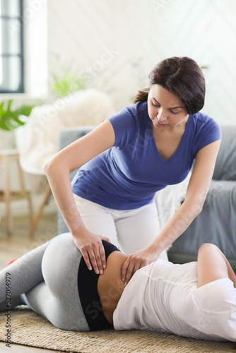 A professional massages the back of a young woman on the floor