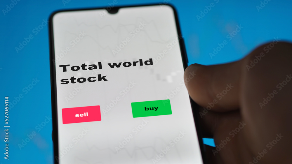 An investor's analyzing the total world stock etf fund on screen. A phone shows the ETF's prices global international exchange to invest An investor's analyzing the total world stock etf fund on screen. A phone shows the ETF's prices global international exchange to invest