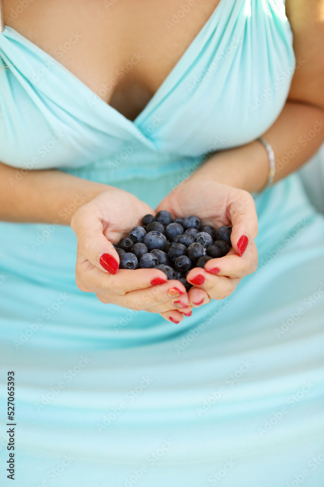 Women’s hands with manicure hold a lot of blueberries