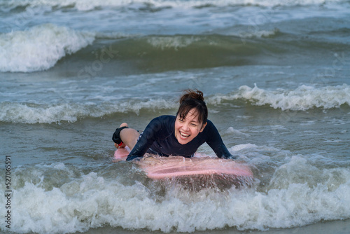 Asian girls lie on surfboards and practice surfboarding with the waves in the sea. water sports concept © Supavadee