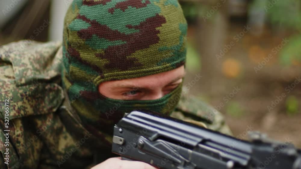 Close-up of a masked soldier preparing to fire and pointing the machine gun towards the camera