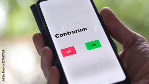 An investor's analyzing the contrarian etf fund on screen. A phone shows the ETF's prices stocks to invest