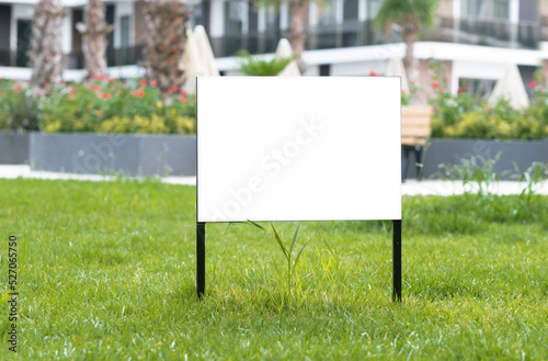 Empty sign, advertising mock-up, banner on grass near pavement in city green park.Copy space for text.Information board on white background. 