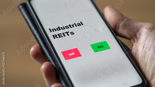An investor's analyzing the reit on screen. A phone shows the ETF's prices industrial REITs
