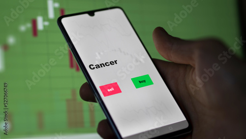 An investor's analyzing the stocks on screen. A phone shows the ETF's prices cancer