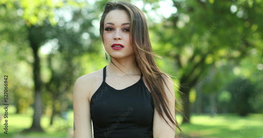 Pretty beautiful millennial girl standing in outdoor park