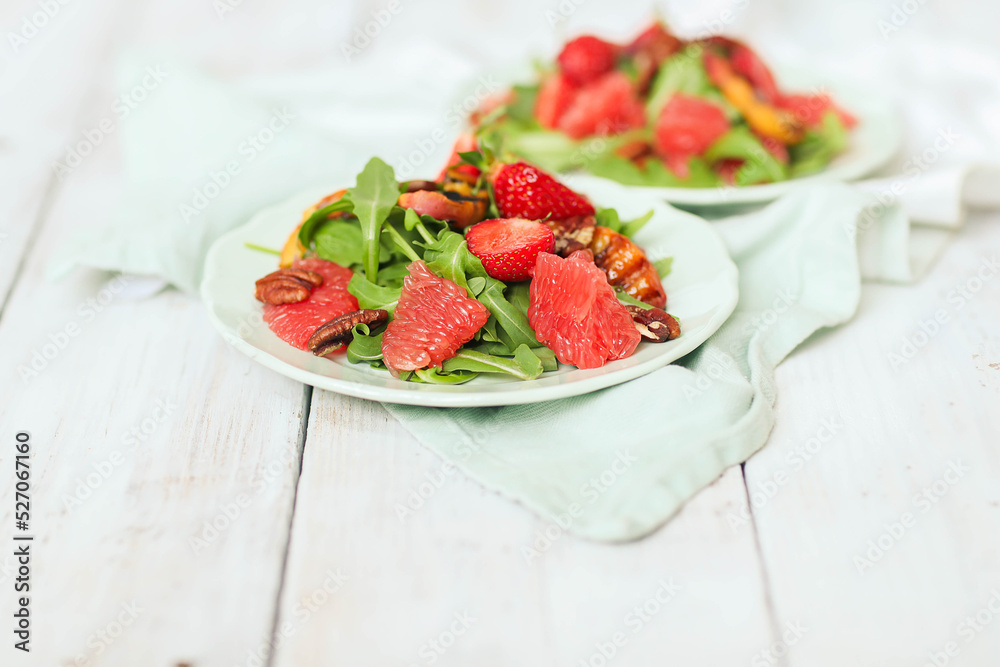 Summer tasty salad with grapefruit , strawberries, arugula and pecan nut in the plate