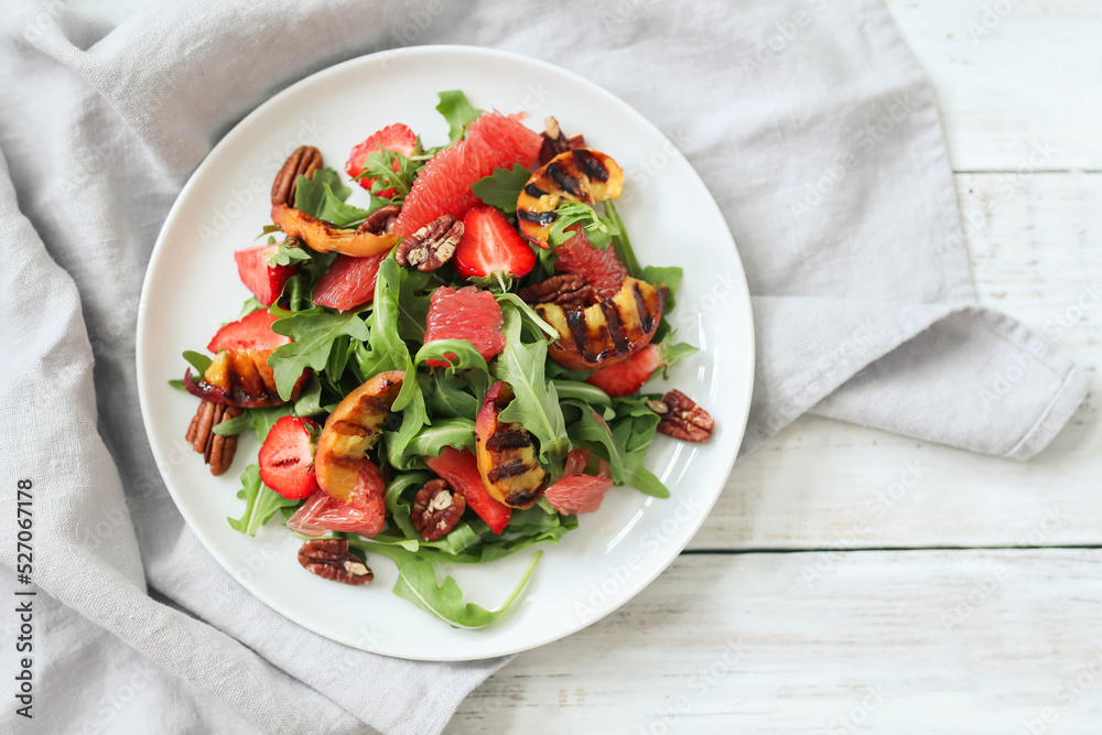 Summer yummy salad with grapefruit , strawberries, arugula and pecan nut in the white plate