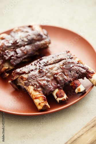 Delicious pieces of fried ribs in the red plate on a wooden background