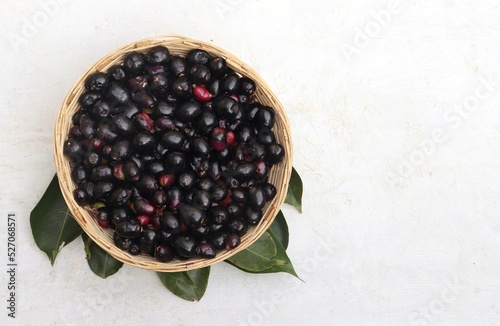 Top View of Jamun or Black Plum Fruit a Bamboo Basket with Leaves Isolated on White Background with Copy Space, Also Known as Malabar Plum, Syzygium Cumini or Jambolan photo