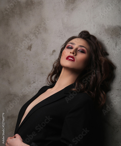 A photo of a young beautiful woman model in black posing for camera © racool_studio