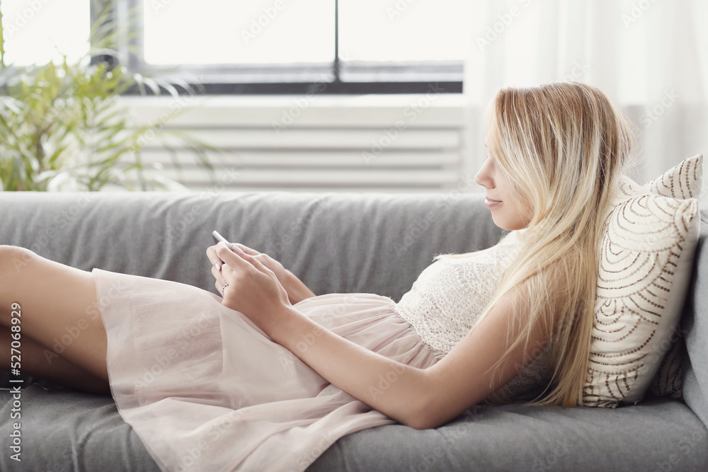 A picture of a beautiful young blonde woman holding a digital tablet and lying on the couch A picture of a beautiful young blonde woman holding a digital tablet and lying on the couch