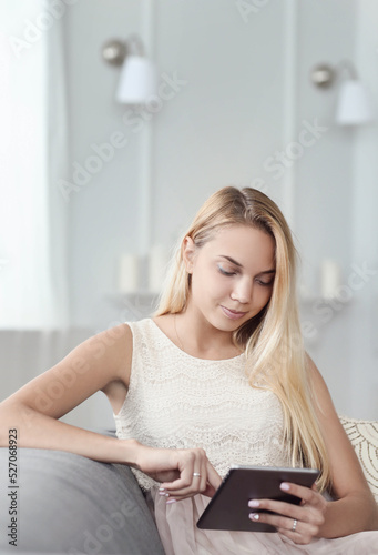 A picture of a beautiful young blonde woman holding a digital tablet and sitting in the chair Free Download A picture of a beautiful young blonde woman holding a digital tablet and sitting in the chair - GFXLoad