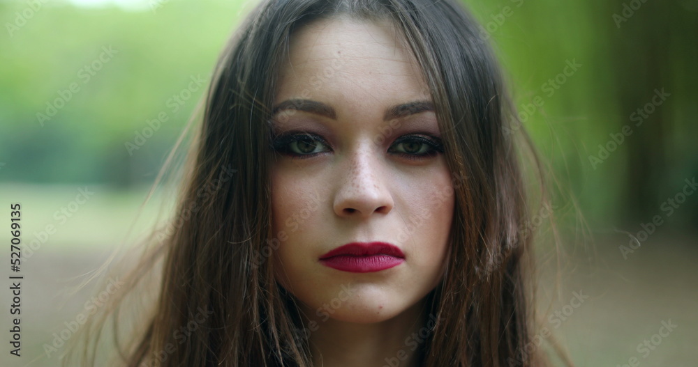 Portrait of serious young woman in 20s looking to camera in outdoors Portrait of serious young woman in 20s looking to camera in outdoors
